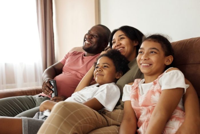 Mother and father sitting on couch with two children laughing